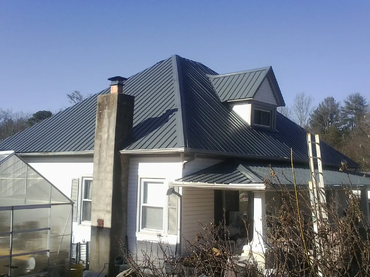 Dark blue standing seam metal roof on a white farmhouse with dormer — Slate & Tile Roof Repair by Roofing Brothers in Matawan
