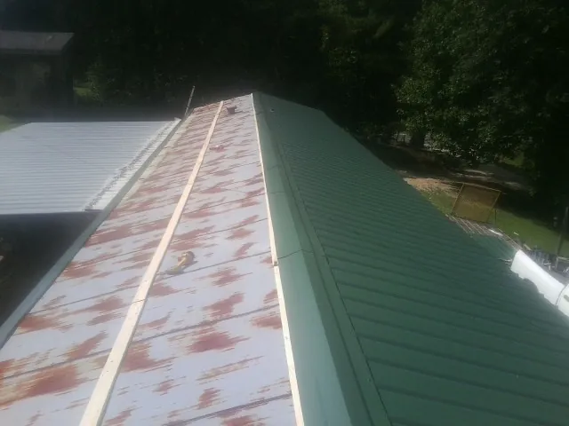 Old rusted panels beside newly installed green metal roofing — Wind Damage Roof Repair by Roofing Brothers in Matawan
