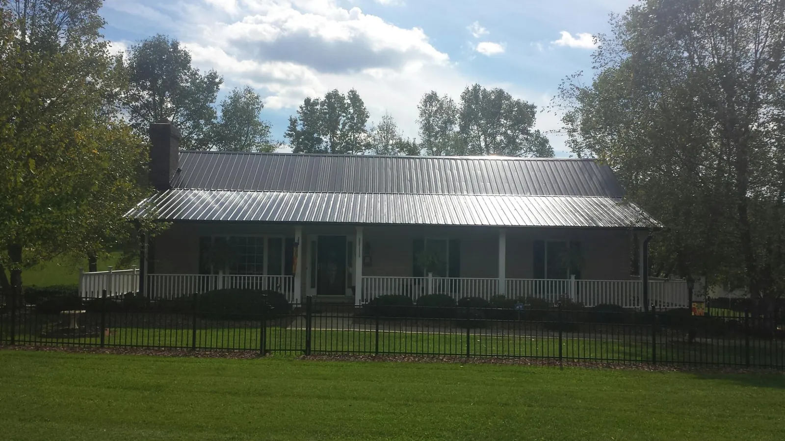Gray metal roof on a brick ranch with a full width front porch — Gutter Guard Installation work by our crew in Matawan