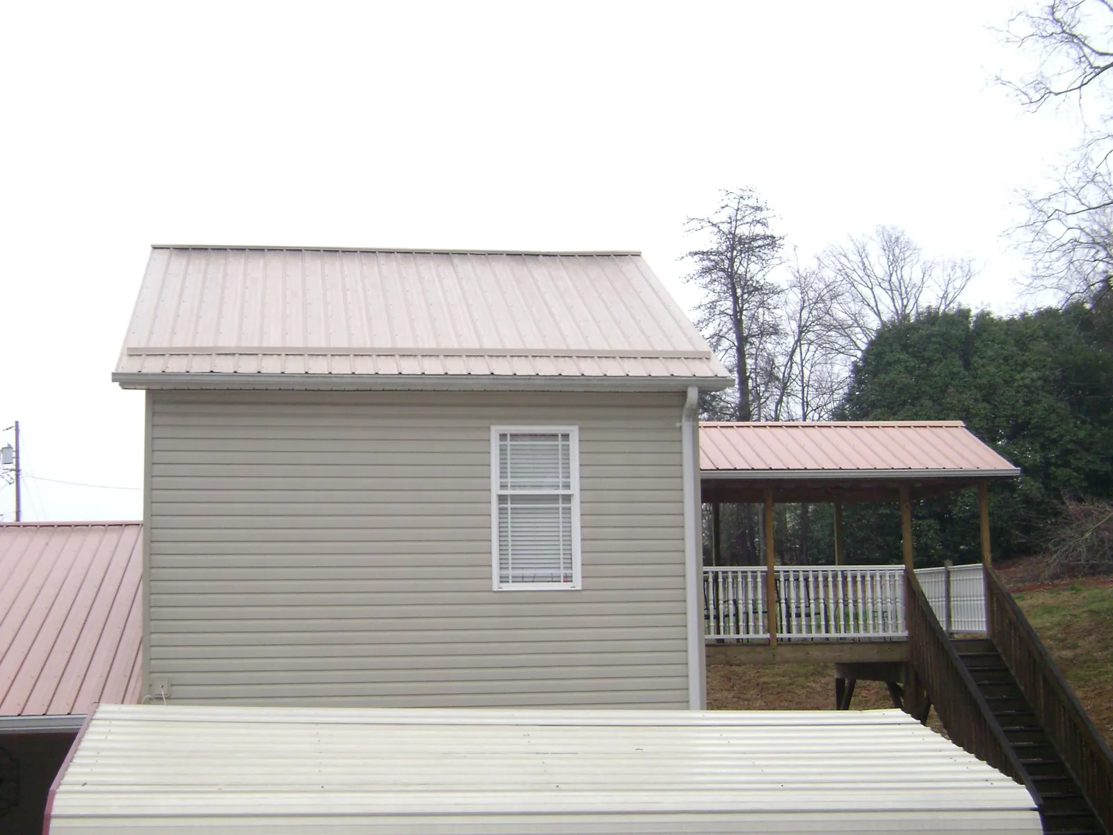 Tan metal roofs on a two story addition and attached porch, from a Roof Replacement job in Matawan