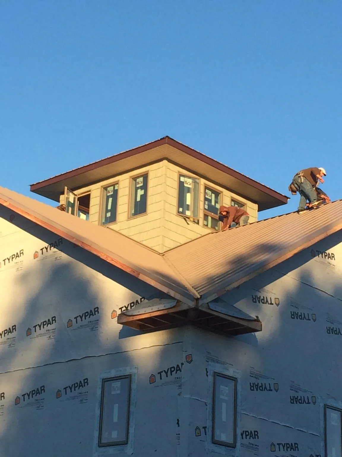 Roofers working around a rooftop cupola on a new metal roof at sunset — Roof Waterproofing in Matawan by Roofing Brothers